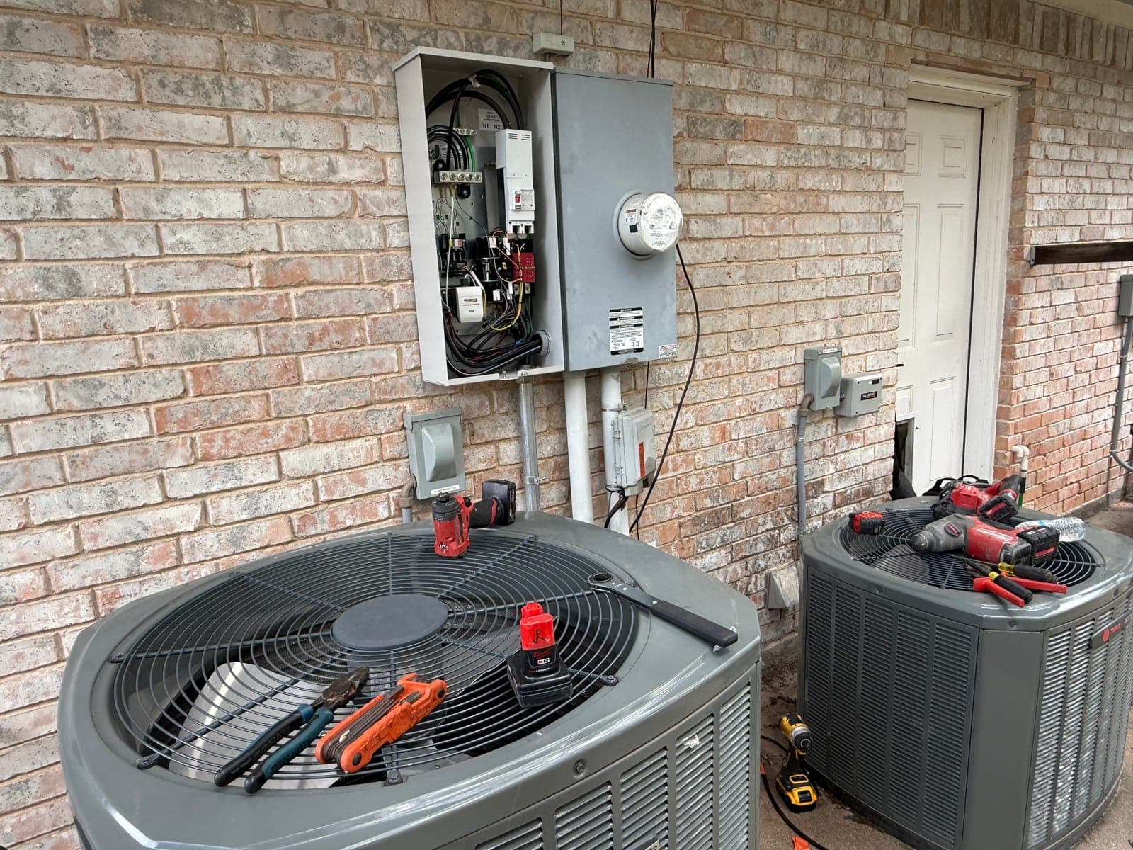 An open electrical panel and an air-conditioning condenser at the side of a house during an Armored Power Systems site assessment.